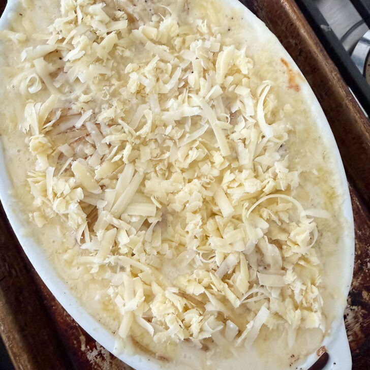 Shredded Gruyere cheese scattered over the top of the potato gratin.