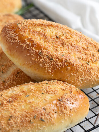 Rosemary Parmesan sandwich buns on a cooling rack.