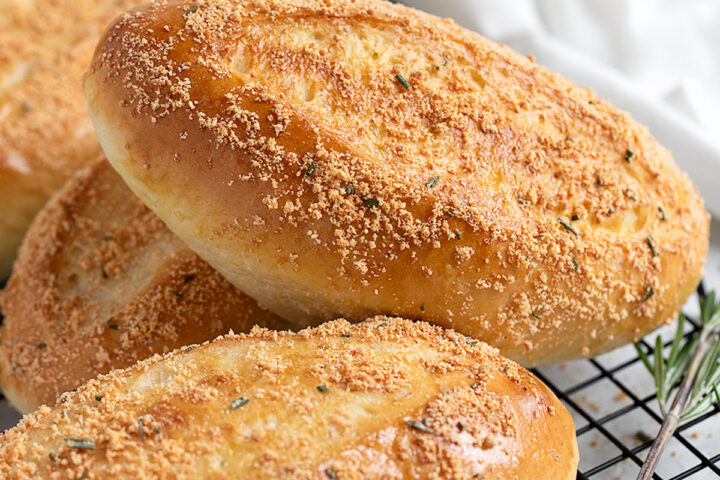 Rosemary Parmesan sandwich buns on a cooling rack.