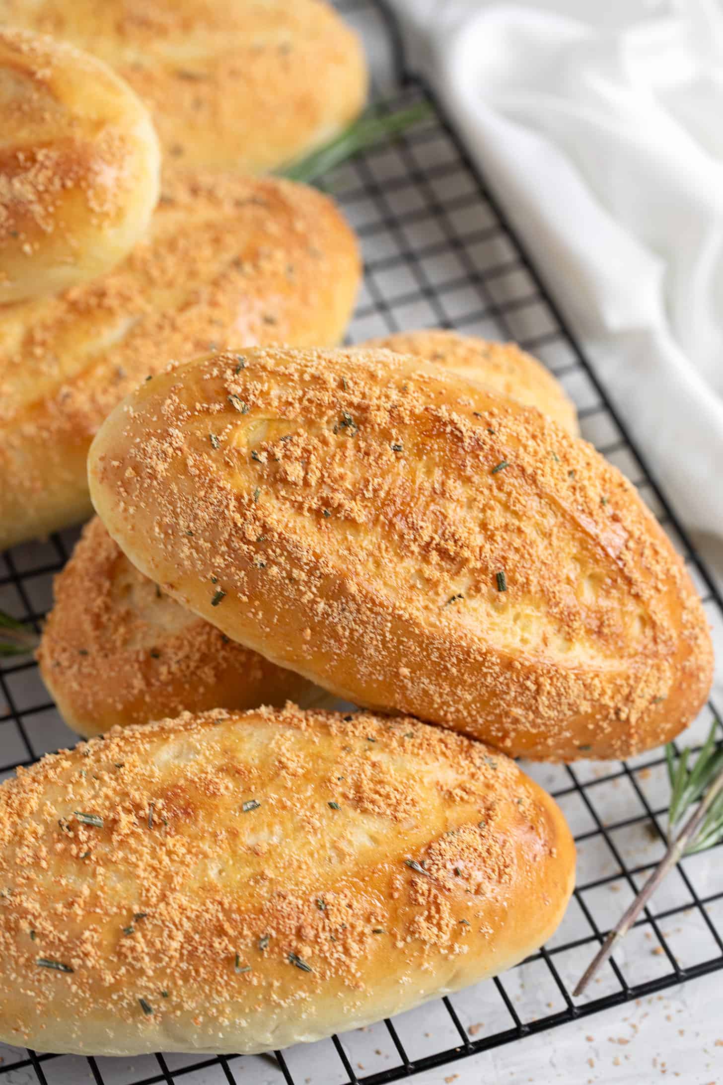 Rosemary Parmesan sandwich buns on a wire cooling rack.