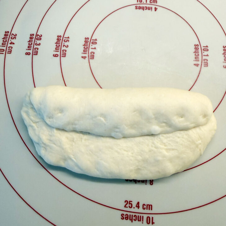 Folding one edge of the oval down to the centre.
