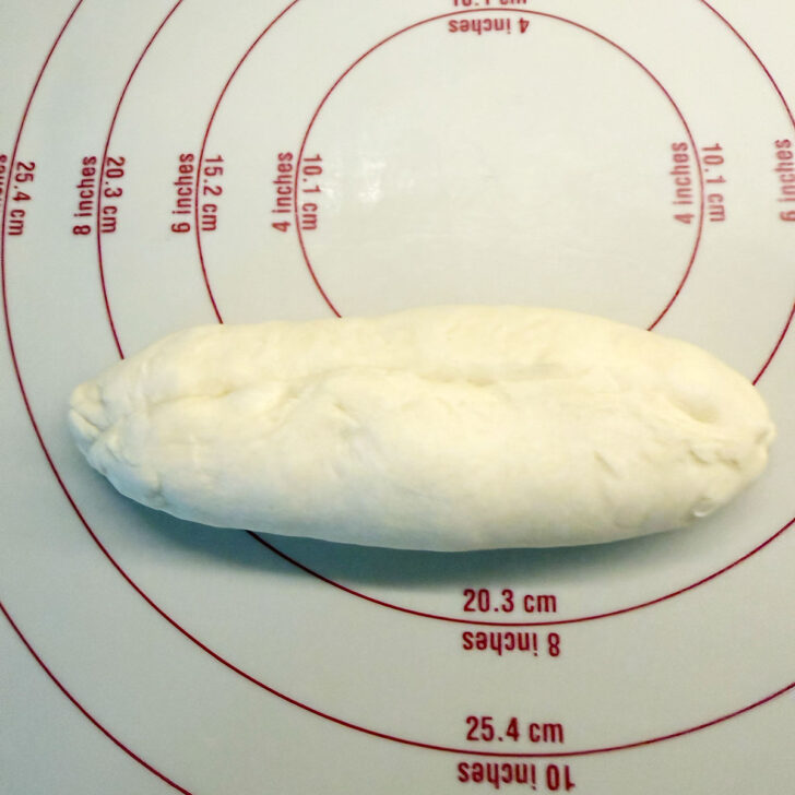 Pinching the seam of the rolled dough together.