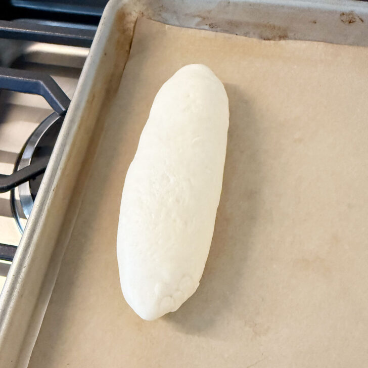 Shaped bun placed on a parchment-lined baking sheet.