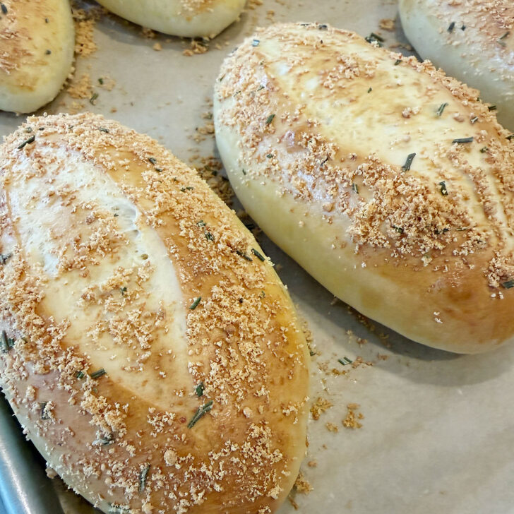 Baked rosemary Parmesan sandwich buns on the baking sheet.