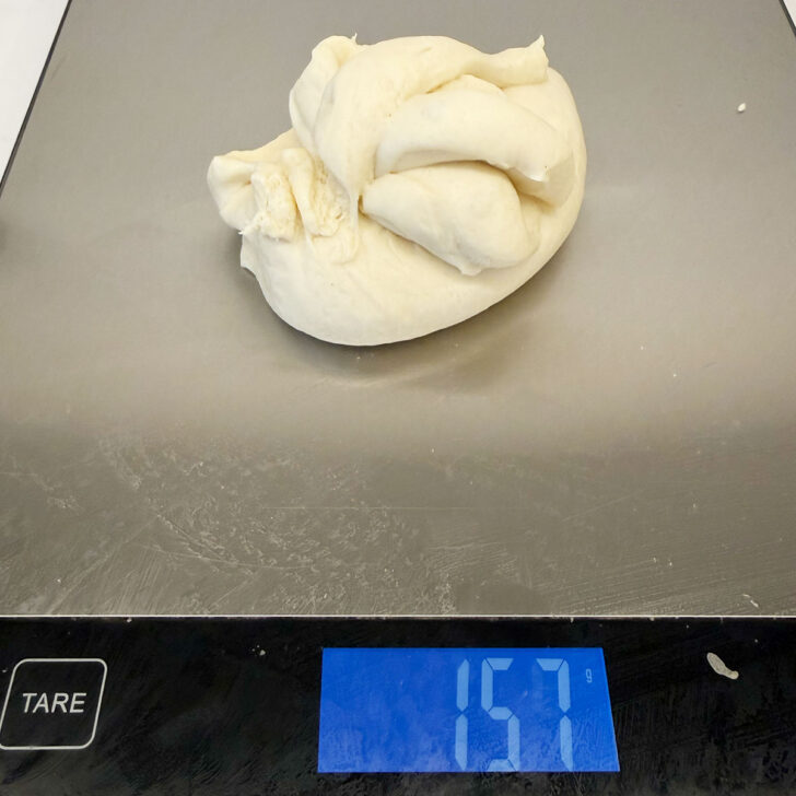 Weighing out the dough balls on a kitchen scale.