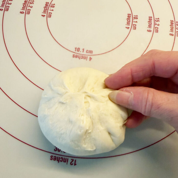 Pinching the dough balls together into a tight ball.