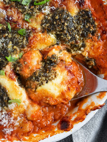 Cherry tomato and pesto baked gnocchi in the baking dish with a spoon.