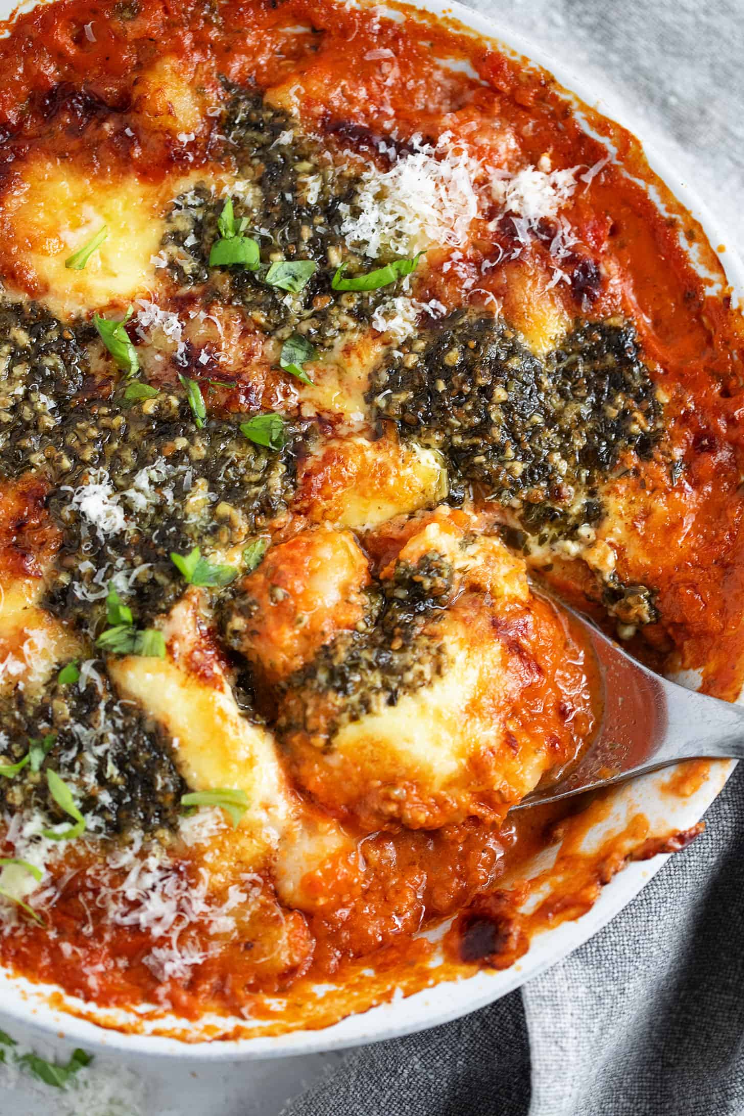 Tomato and pesto baked gnocchi in the dish with a spoon.