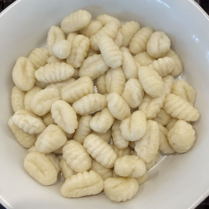 Boiled gnocchi added to a casserole dish.