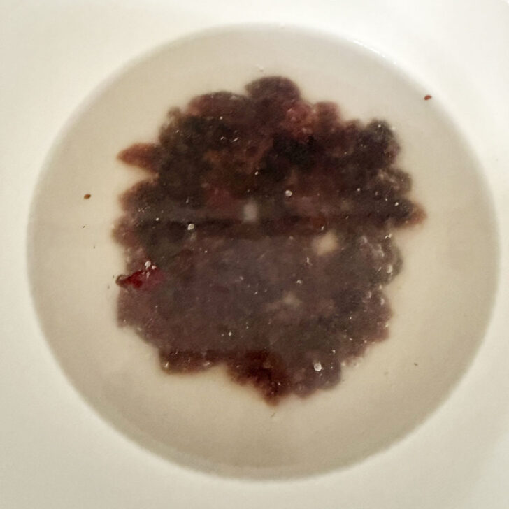 Soaking dried cranberries in hot water in a small bowl.