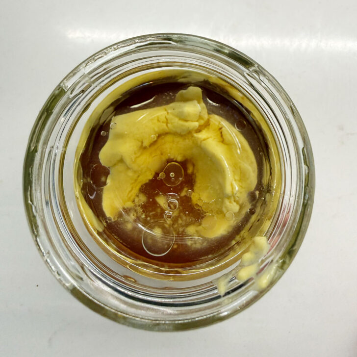 Maple mustard vinaigrette ingredients added to a small jar.