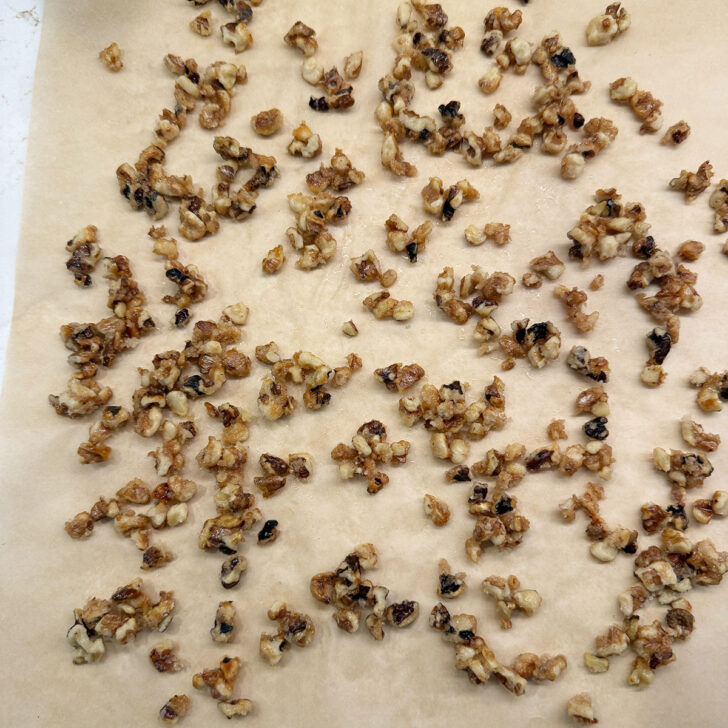 Quick-candied walnuts scattered onto a sheet of parchment paper.