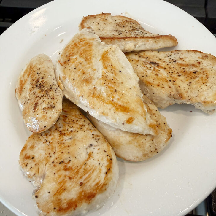 Browned chicken breast cutlets removed from the skillet to a plate.