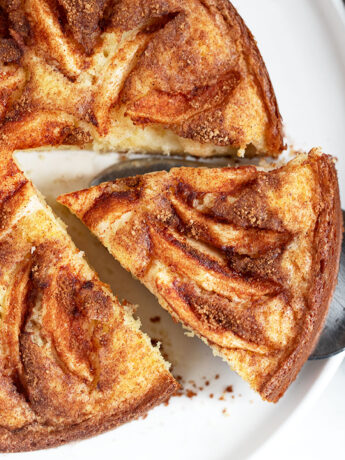 Dutch apple cake on a serving plate with a slice cut out.