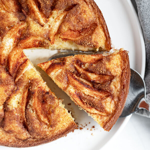 Dutch apple cake on a serving plate with a slice cut out.