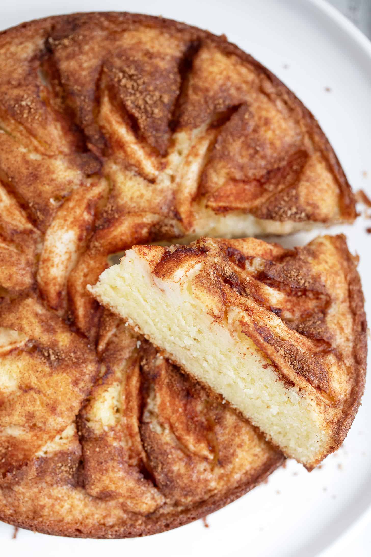 Dutch apple cake on a serving plate with a slice cut out.