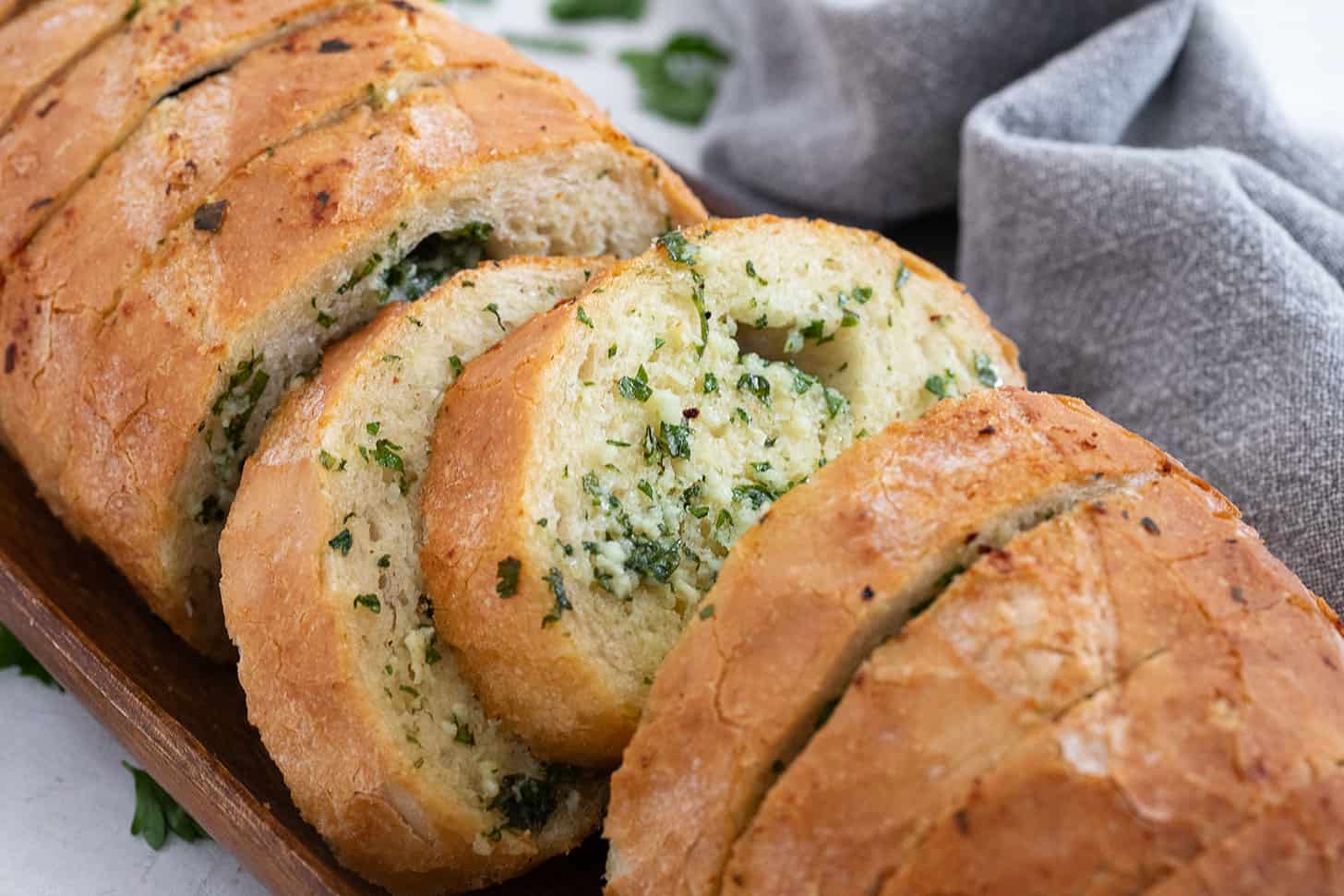 Easy herb and garlic bread loaf made from a whole bread loaf, sliced on a serving board.