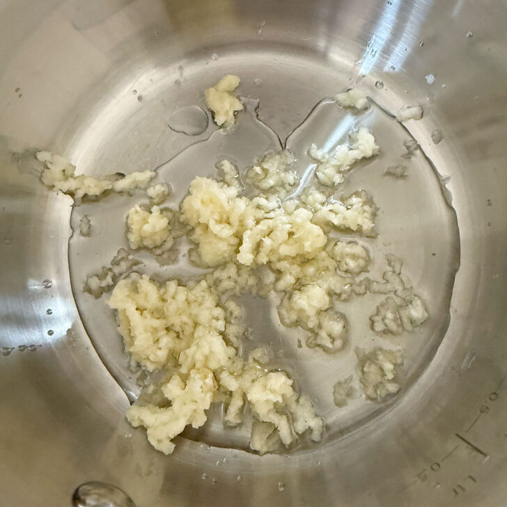 Heating the minced garlic and olive oil in a saucepan.