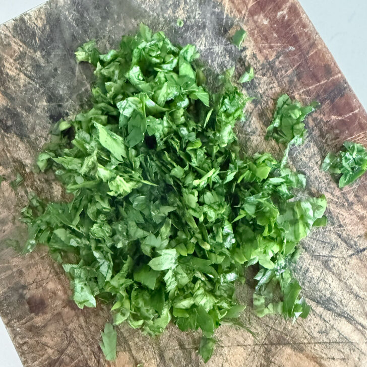 Fresh herbs chopped on a cutting board.