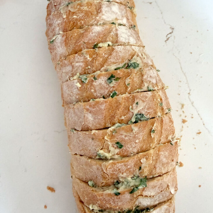 Sliced loaf of bread after spreading the slices with the herb and garlic butter.