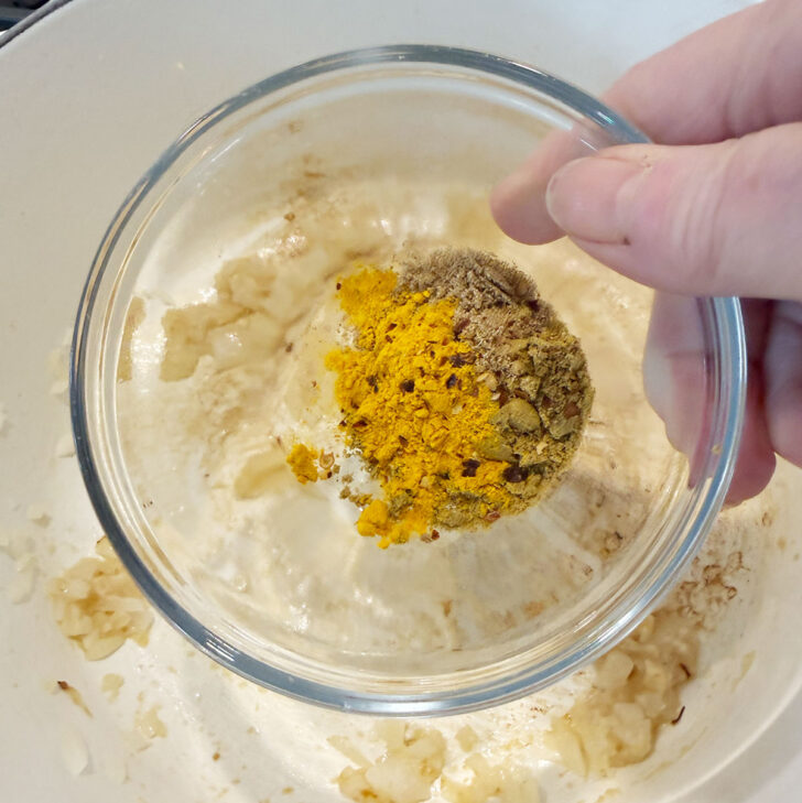 Adding spices to the soup pot.