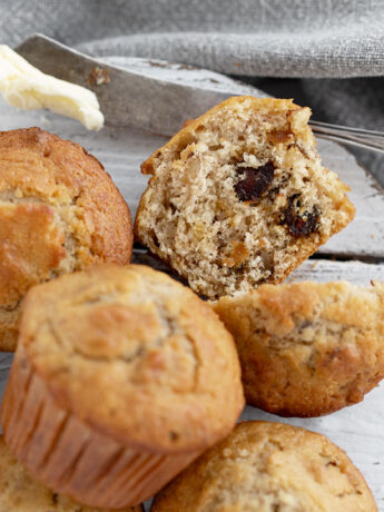 Maple walnut date muffins on a serving board with one cut in half.