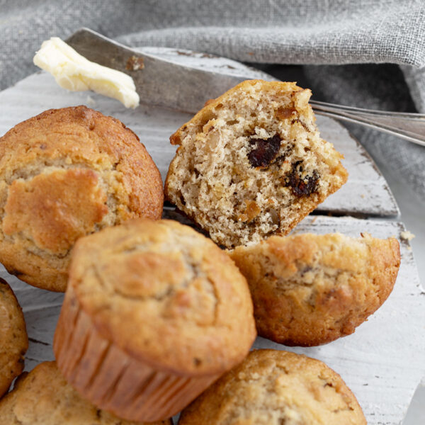 Maple walnut date muffins on a serving board with one cut in half.