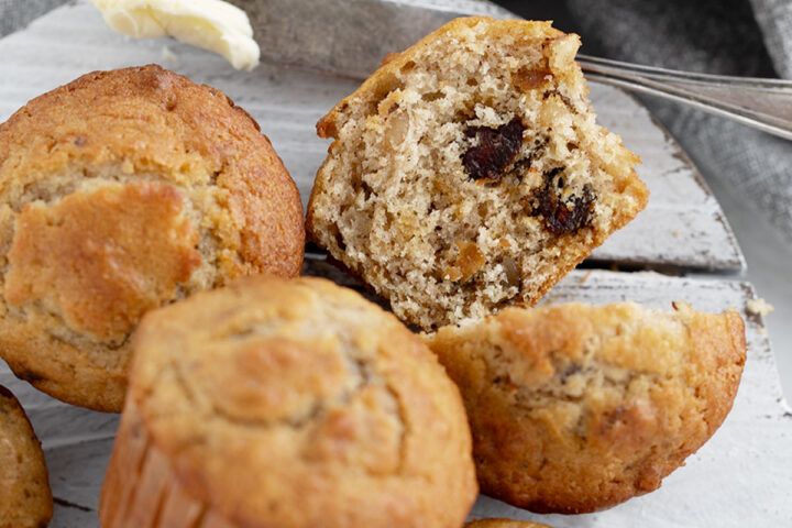 Maple walnut date muffins on a serving board with one cut in half.