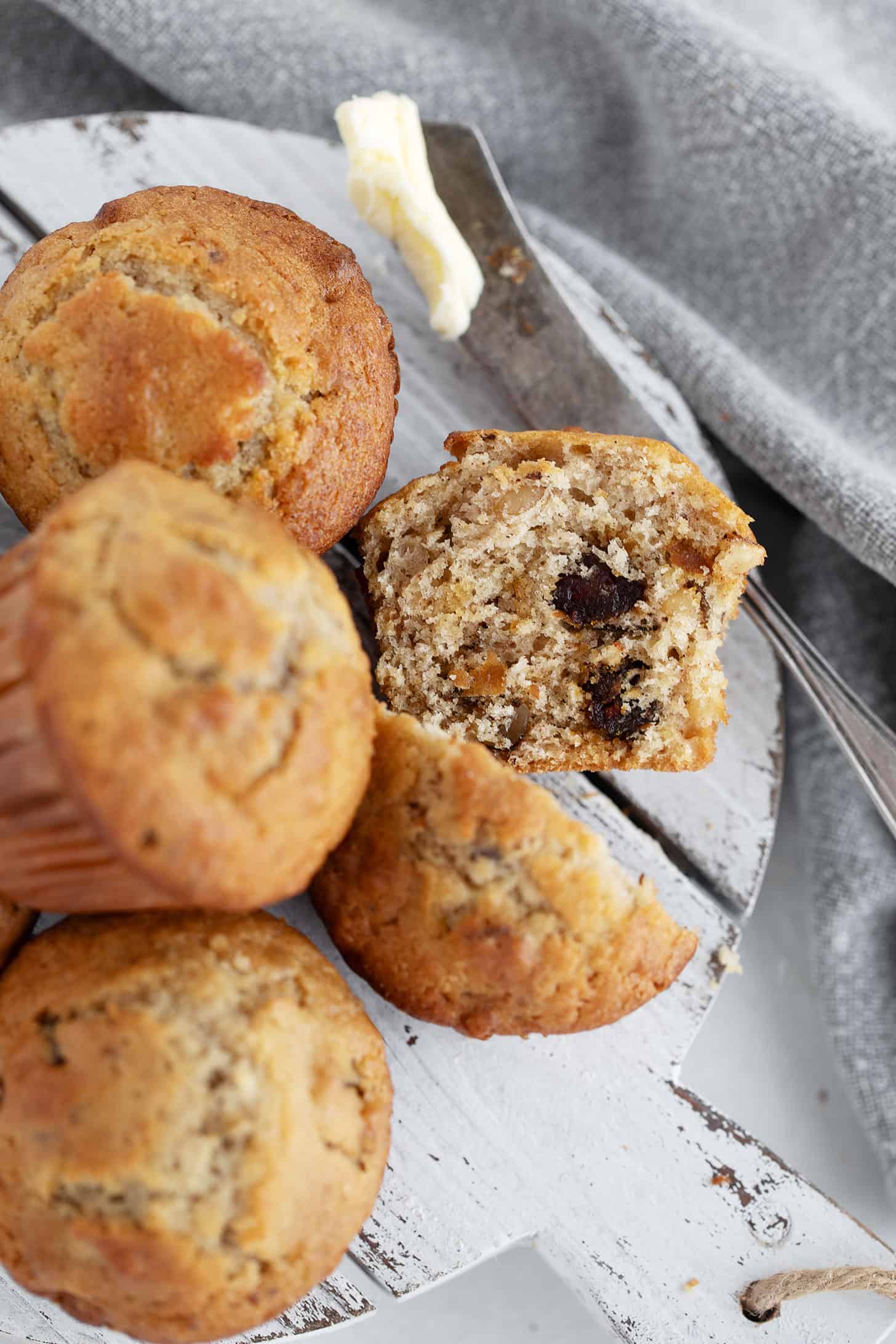 Maple walnut date muffins on a serving board with one cut in half.