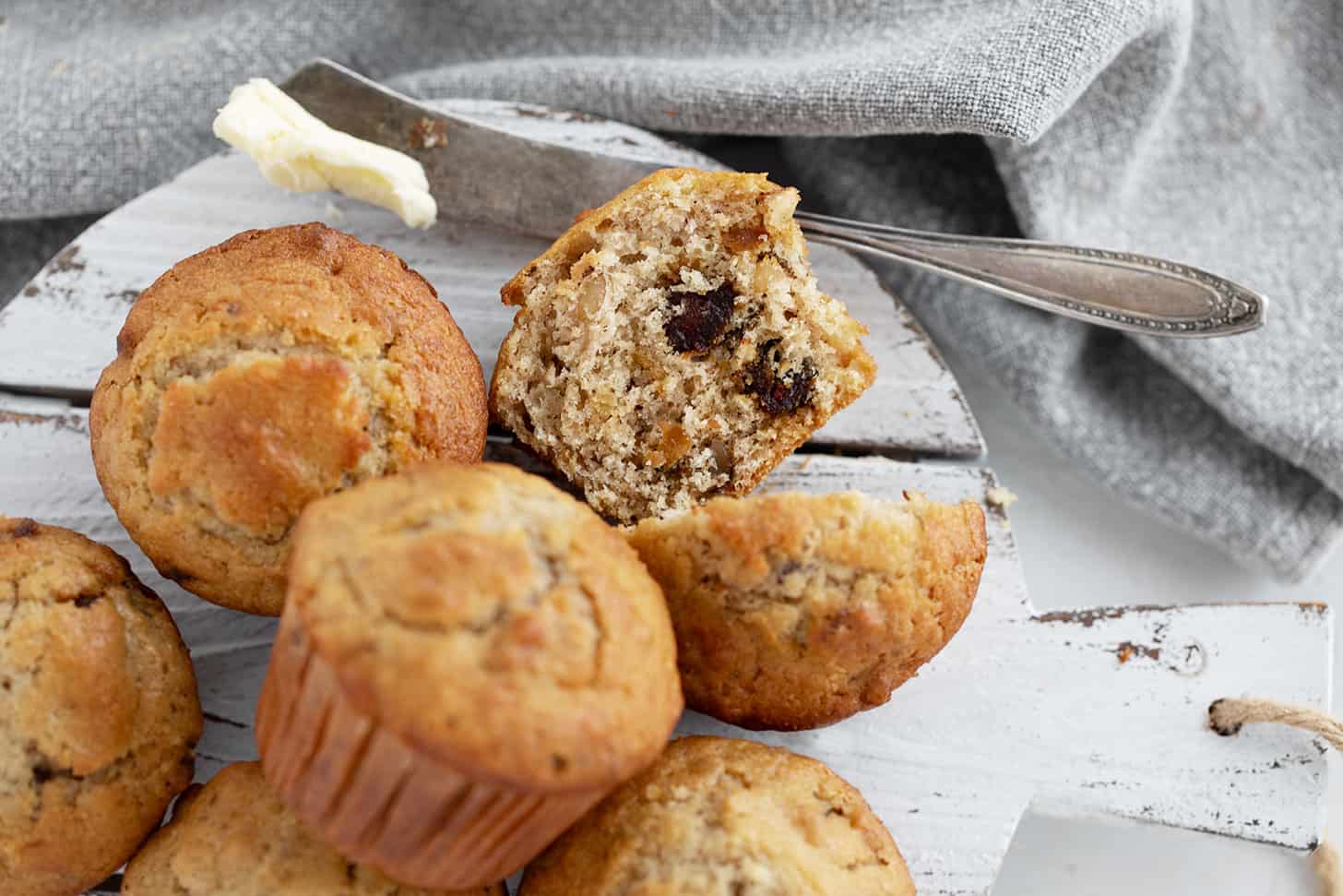 Maple walnut date muffins on a serving board with one cut in half.