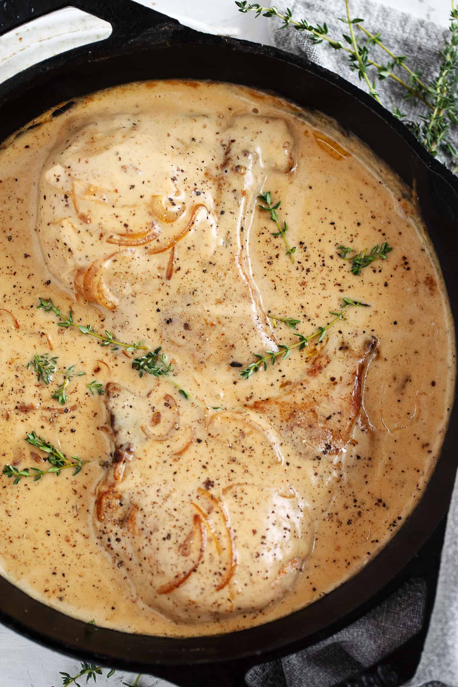 Smothered pork chops in a cast iron skillet.