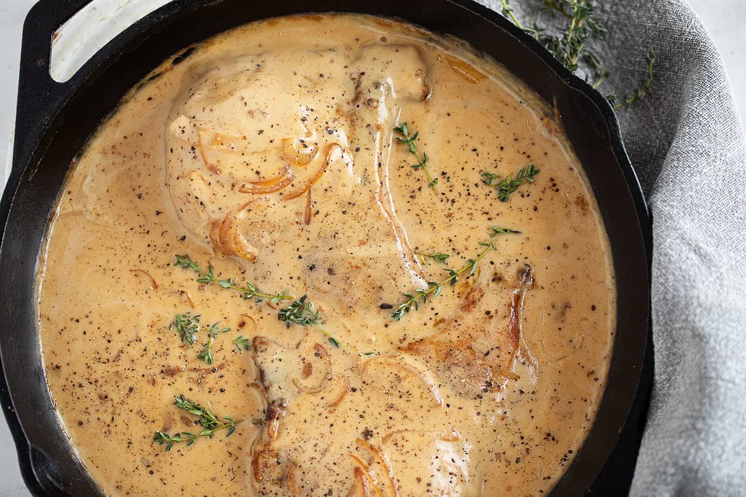 Smothered pork chops in a cast iron skillet.
