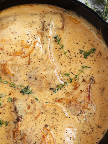 Smothered pork chops in a cast iron skillet.