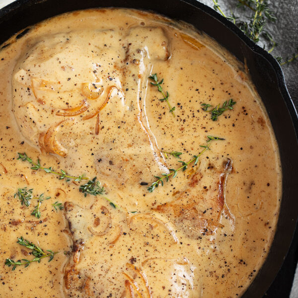 Smothered pork chops in a cast iron skillet.