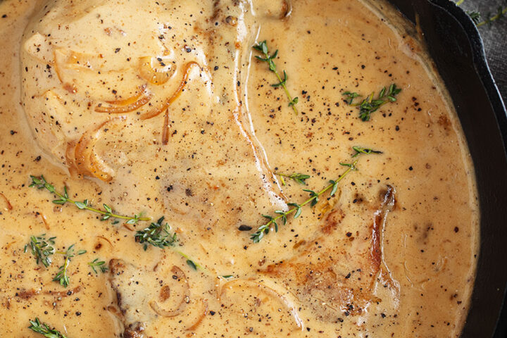 Smothered pork chops in a cast iron skillet.