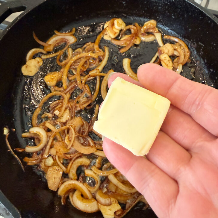 Adding butter to the skillet with the onions and garlic.