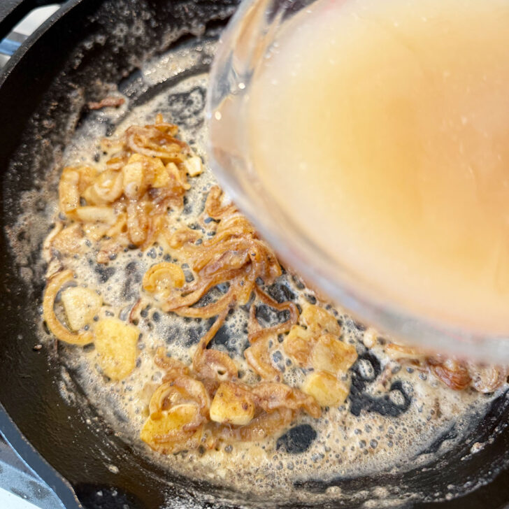 Adding chicken broth to the skillet.