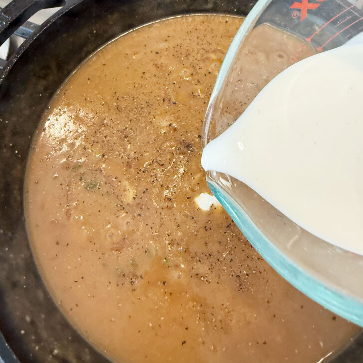 Finishing the sauce for the smothered pork chops with cream.